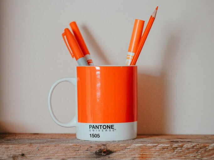 Orange Pantone Farbe auf einer Tasse mit orangen Zahnbürsten darin